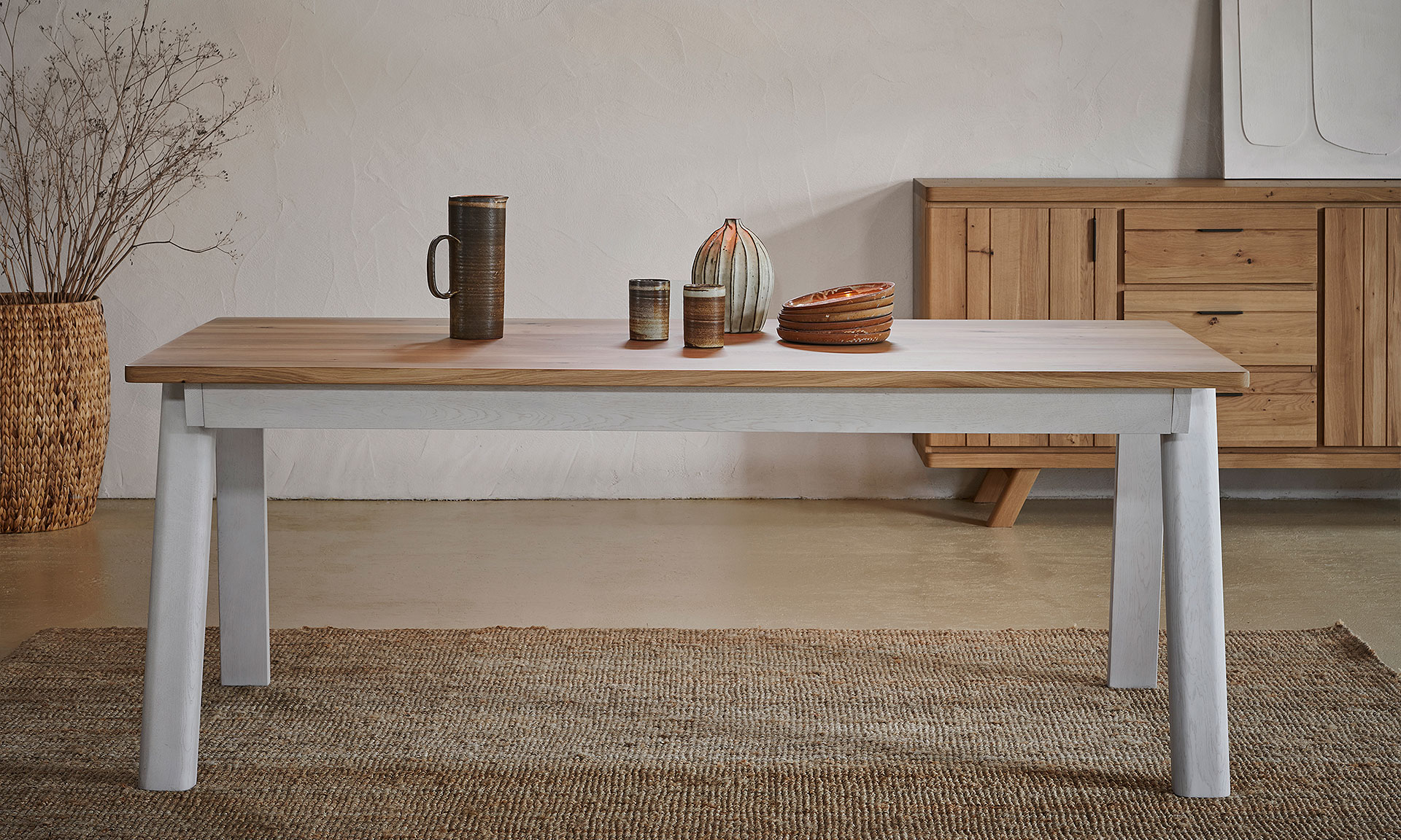 Photo d'ambiance présentant une table et une enfilade décoré d'éléments décoratif en céramique, Avec une finitions bois chêne massif peinte en partie en blanc mat.