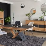 Photo d'une salle à manger avec une collection comportant une table de repas, une enfilade et une vitrine. Les meubles présente des finitions chêne teinte ton brut brossé et des éléments céramique marbré gris.