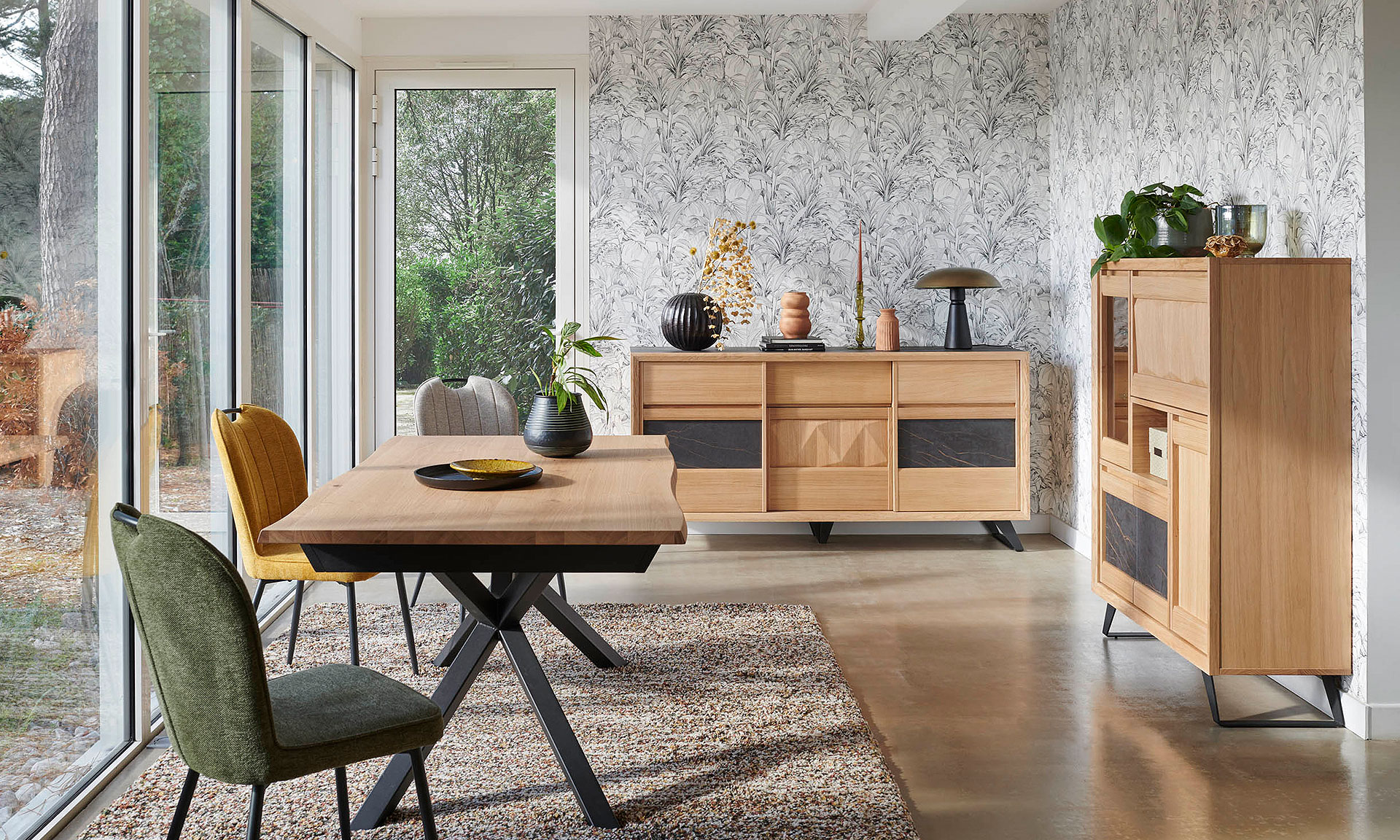 Photo d'une salle à manger avec une collection comportant une table de repas, une enfilade et un bibus. Les meubles présente des finitions chêne teinte ton brut brossé et des éléments céramique marbré gris.