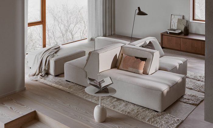 Photo d'un salon présentant un ensemble d'assises modulables. Les éléments sont revêtus d'un tissu gris clair. L'aménagement comprend une chaise longue, deux chauffeuses et un pouf.